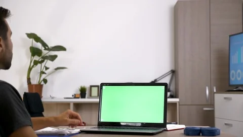 Man at his desk in front of computer with green screen Stock Footage 95314189