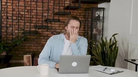 A man at his desk yawns while sitting at a computer. sleep deprivation concept Stock Footage 196119555