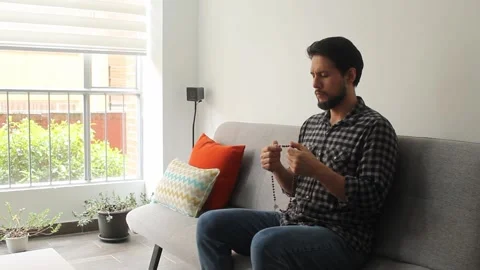 Man with his eyes closed praying the rosary in concentrating attitude Vídeo Stock 340583430