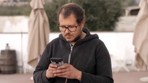 Man in his garden using cell phone. He is very focused on the content of the sms Stock Footage 171819221