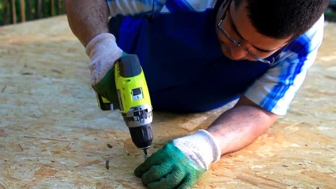 Man at his garden using electric drill, drilling in screw into wood pavement. Stock Footage 110771208