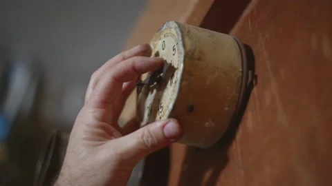 Man with his two hands setting a rusty vintage mechanical timer on the wall. Stock Footage 310768380
