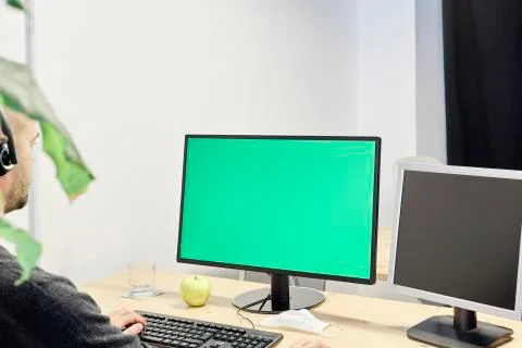 Man at his workplace with a computer and a green screen 库存照片
