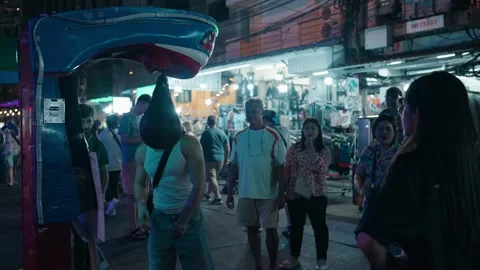 Man hitting arcade punching machine on Bangkok street at night Stock Footage 320396271