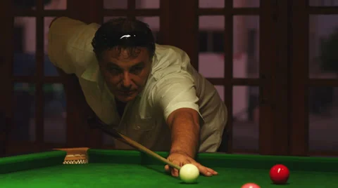 A man hitting a cue ball on a green billiard table and sinking the ball Stock Footage 33847982