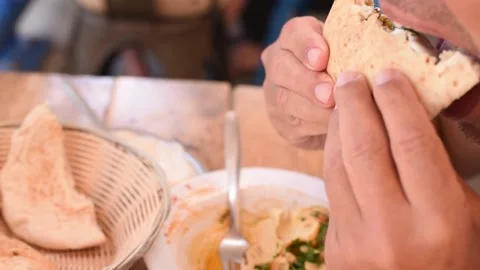 Man hold and eats pita with falafel, tahini olives and pickles inside. Stock Footage 184841815