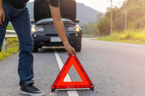 Man hold and put down the red triangle for warning have black color car parki Stock Photos