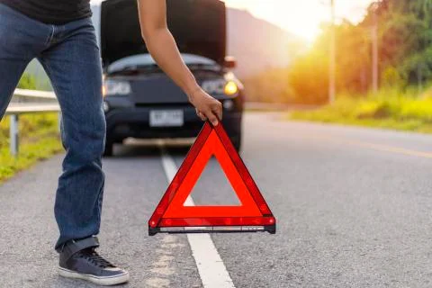 Man hold and put down the red triangle for warning have black color car parki Stock Photos