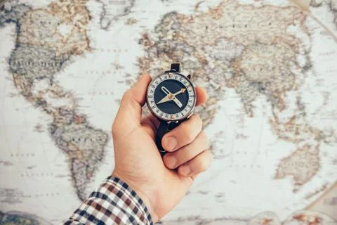 Man hold compass to check the direction with blurred map background. Travel a Stock Photos