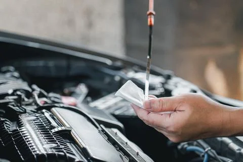 Man hold dipstick to check the engine oil level of engine and use white clo.. Stock Photos