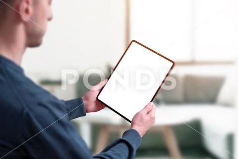 Man hold tablet with isolated screen for mockup. Home interior in background PSD Template