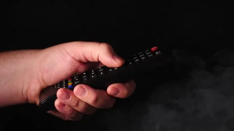 Man holder remote control flipping through channels smoke rising represent scary Stock Footage 206654173