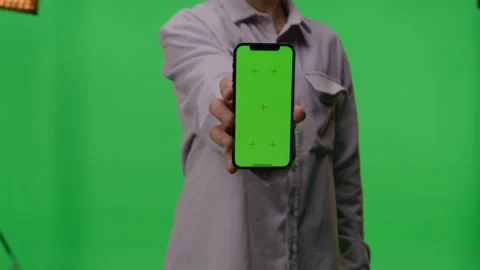 Man Holding And Pointing Mobile Phone With Green Screen While Standing In Front Stock Footage 196220463