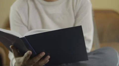 Man holding and reading a book, turning pages Stock Footage 272315532