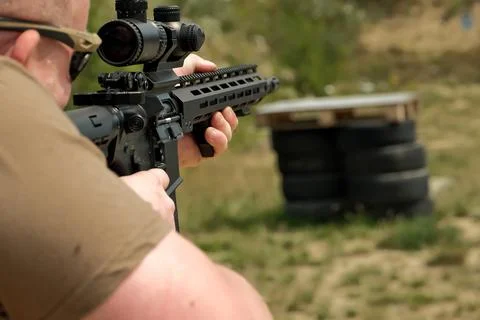 A man is holding an automatic weapon. a man looks into the sight of a militar 写真素材