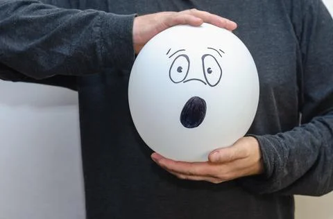 Man holding balloon with face drawn in front of him. White balloon with hand- Stock Photos