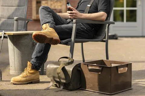 Man holding a beer bottle while sitting outside in the sun and having a break Stockfoto's
