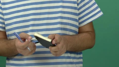 Man Holding Black Notebook and Taking Notes with Green Screen Background Stock Footage 344677396