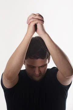 A man holding a black t-shirt lowered his head and hands folded together rais Stock Photos
