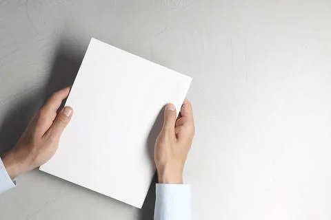 Man holding blank notebook at light grey table, top view. Mockup for design Stock Photos