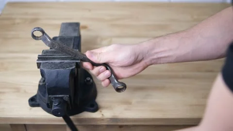 A man holding a bolt wrench in a black vise with a screw handle and a cast-iron  Stock Footage 148038150