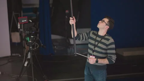 Man holding boom microphone adjusting in studio broadcast video production Stock Footage 317550970