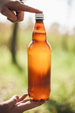 Man holding a bottle of beer between his hands outdoors Stock Photos
