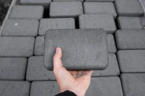 Man holding a brick. Stack of paving stone on construction site. Bricks for Stock Photos