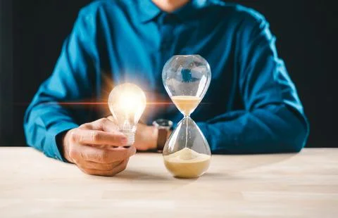 Man holding bright lightbulb idea and hourglass with flowing sand, showing .. 写真素材