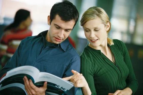 Man holding brochure, woman looking over his shoulder, pointing to page Stock Photos