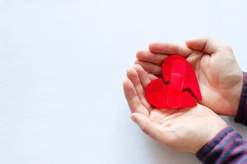 Man holding broken heart with a patch on a white background Stock Photos