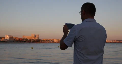 Man Holding Browsing Digital Tablet Spectacular Sunset Light Seaside View Travel Stock Footage 67965346