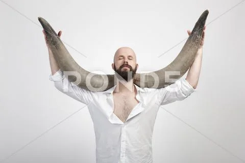Man holding buffalo horns, eyes closed Stock Photos