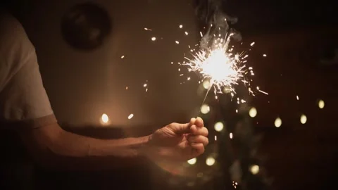Man holding burning sparkler in front of christmas tree Stock Footage 292933740