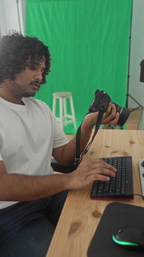 Man holding camera and typing on keyboard in studio with green screen backd.. Stock Footage 337396255