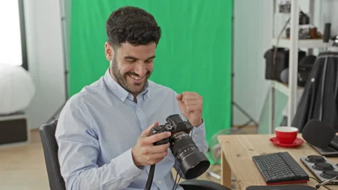 Man holding camera with bare hands checking lens and controls beside desk, .. Stock Footage 339175513