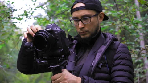 A man holding a camera. Photographer with a camera in a wooded area. Man in a Video stock 139870909