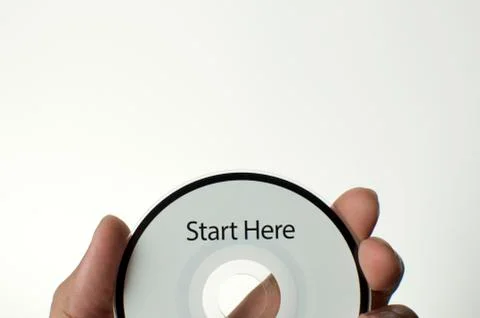 A man is holding a cd with a start here message Stock-Fotos