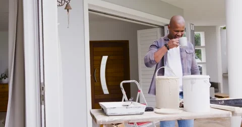 Man holding ceramic mug, sipping after prepping paint cans roller at porch, copy Stock Footage 344105522