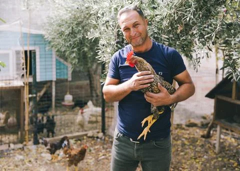 Man holding chicken in a quiet backyard 스톡 사진