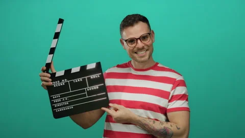 Man holding clapperboard with smile against isolated green background weari.. Stock Footage 310028651