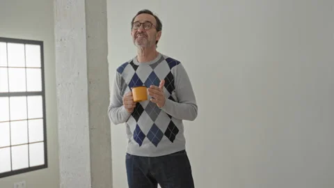 Man holding a coffee cup with both hands, smiling and looking aside in a br.. 스톡 동영상 337444261