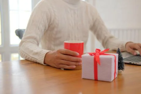 Man holding coffee cup &amp; using computer at home during christmas. xmas new ye Stock Photos