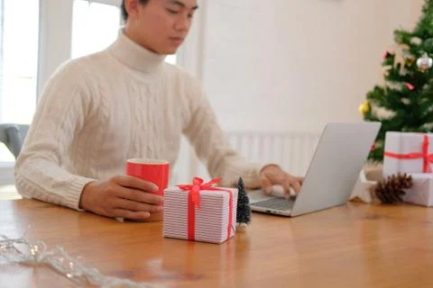 Man holding coffee cup &amp; using computer at home during christmas. xmas new ye Stock Photos