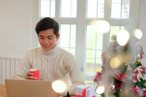 Man holding coffee cup &amp; using computer at home during christmas. xmas new ye Stock Photos