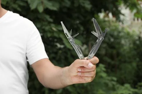 Man holding compact portable multitool outdoors, closeup Stock Photos