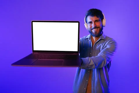 Man holding computer with empty mockup screen wearing headphones, studio 스톡 사진