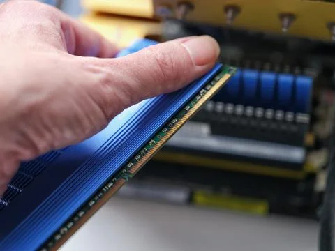 A man holding a computer RAM module with a large heat sink. Stock Photos
