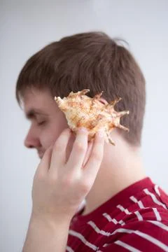 Man holding a conch shell to his ear Stock Photos