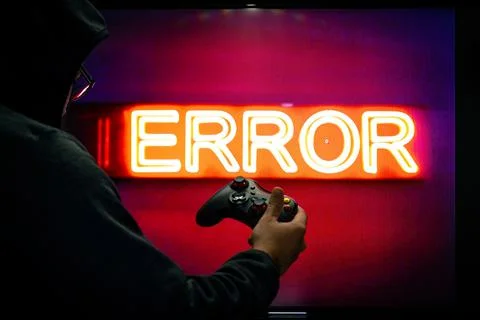 Man holding a controller in front of a screen showing an error message as a g Stock Photos